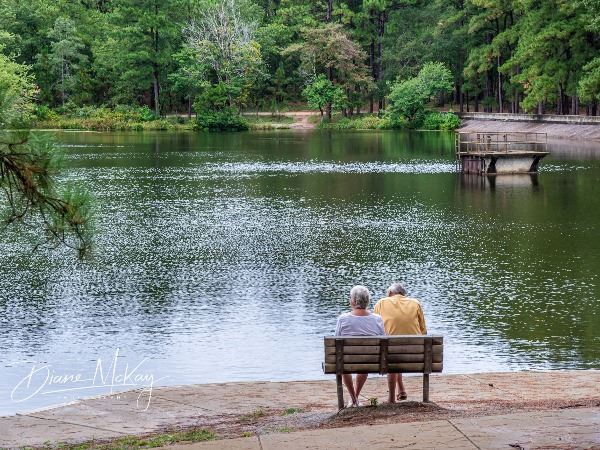 Two people sitting on a bench looking out at the reservoir